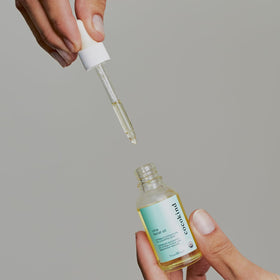 Cocokind chia oil in hand applying a drop to skin to show easy layering and finish