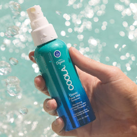 COOLA being sprayed on skin at neck showing easy reapplication and coverage benefit