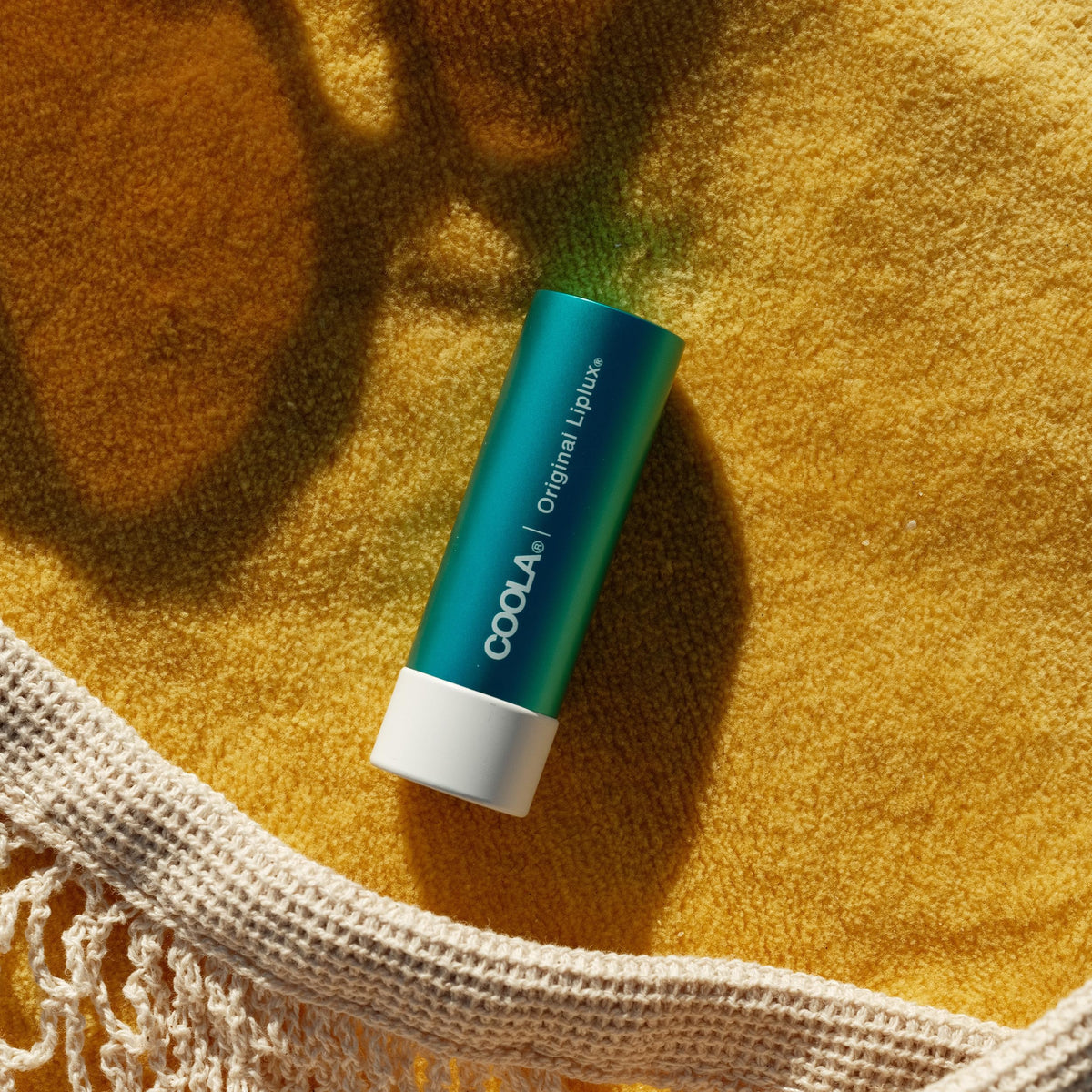 COOLA Liplux in beach setting showing COOLA sun protection for outings