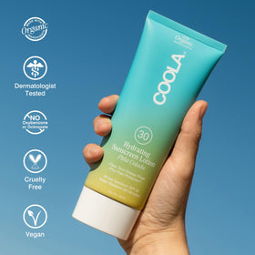 COOLA 5 fl oz bottle beside a smartphone illustrating travel-friendly compact size