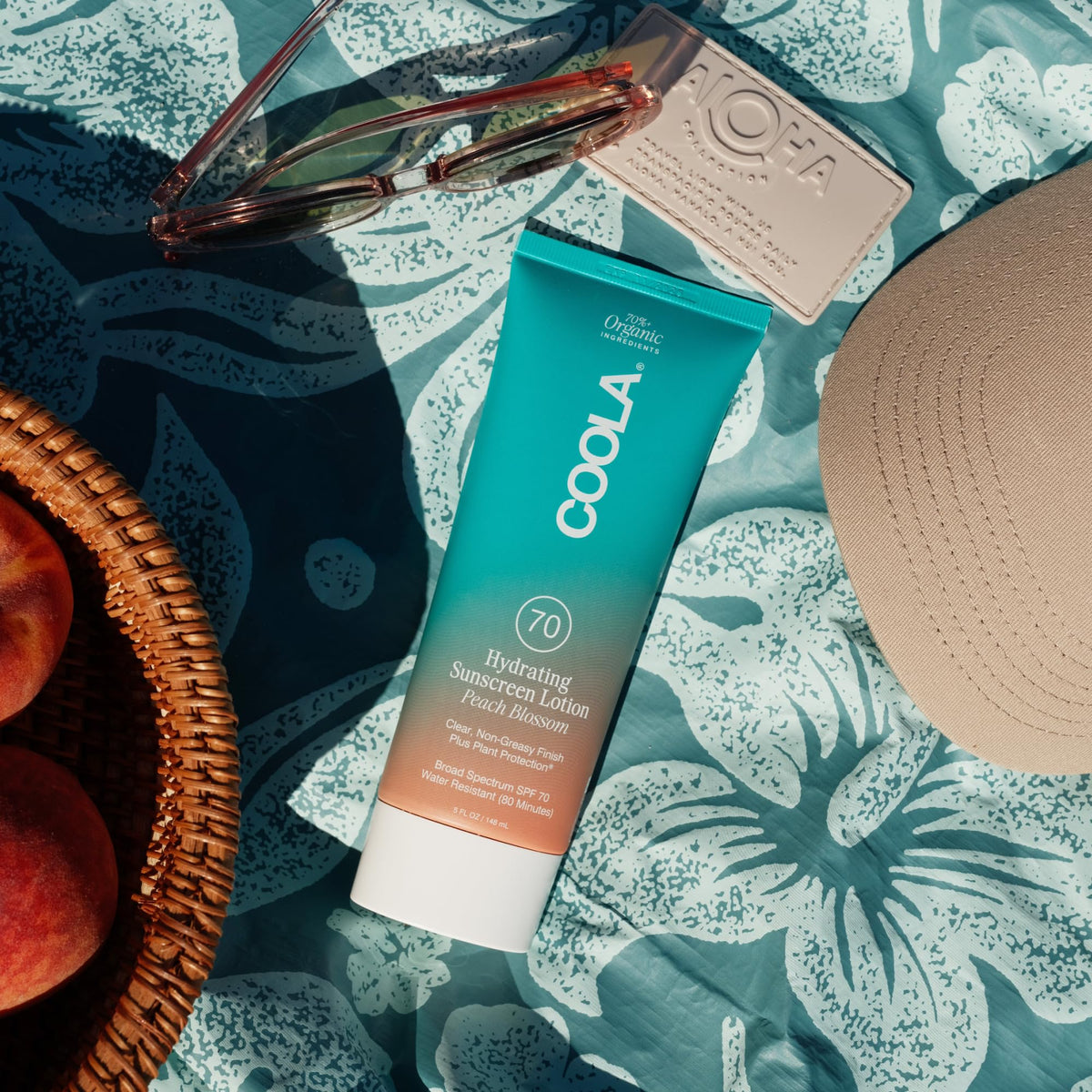 COOLA bottle on beach towel showing portability and travel-friendly protection
