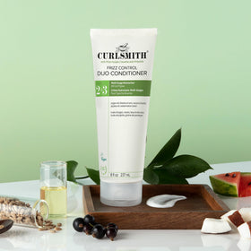 CURLSMITH stylist applying product to curly hair for frizz control