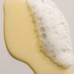 Davines DEDE/ bottle beside common item to show 8.5 oz scale and travel-friendly benefit