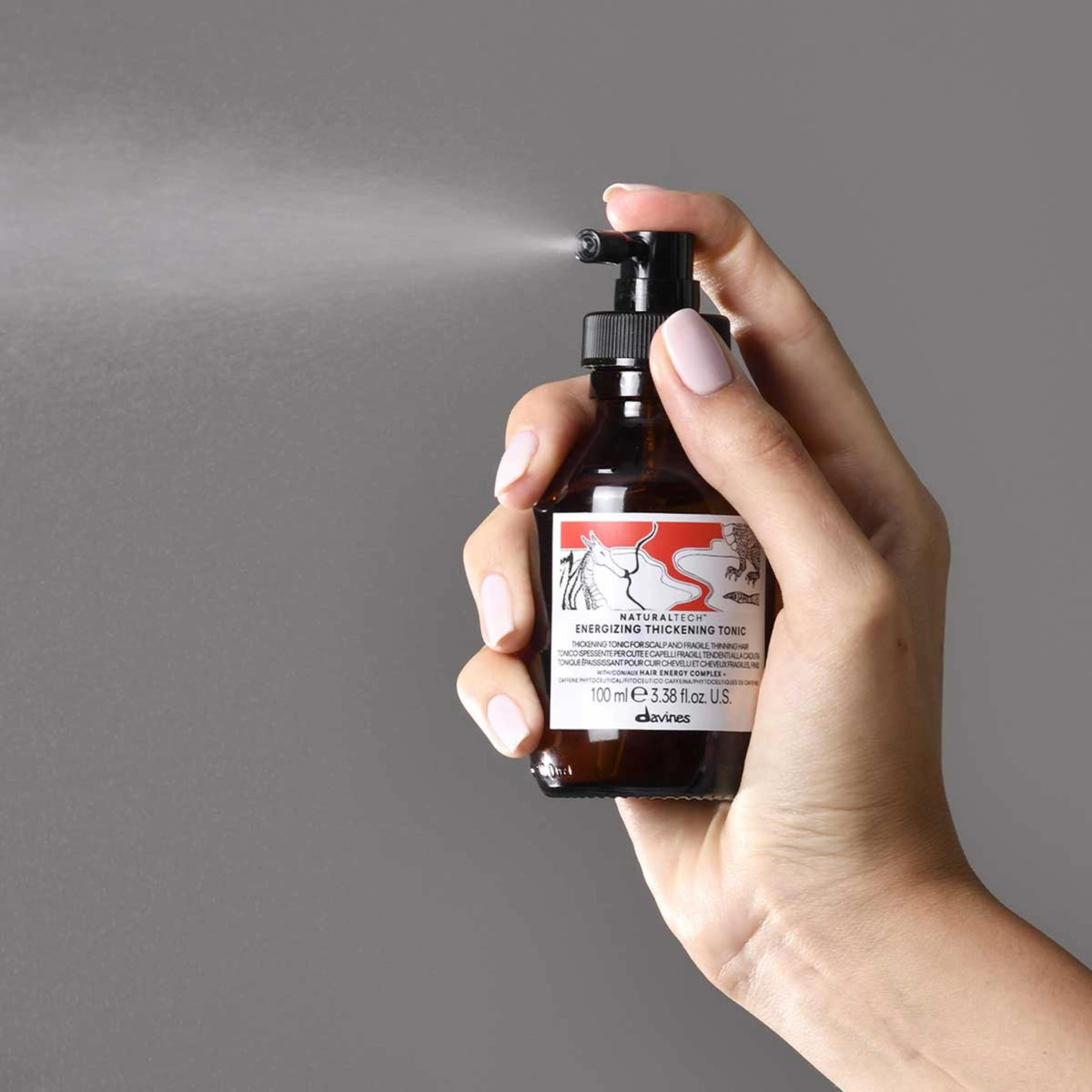 Davines bottle in hand indicating compact travel size and convenience