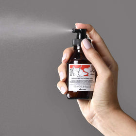 Davines bottle in hand indicating compact travel size and convenience