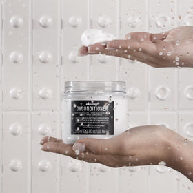 Davines products beside a hand to show scale and travel-friendly sizes benefit