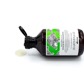 Davines renewing shampoo bottle in hand for size and scale reference
