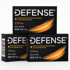 Defense Soap citrus bar next to hand for scale showing compact travel size