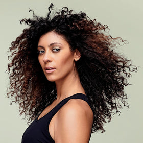 DevaCurl bottle in shower being applied to wet curls to demonstrate easy use