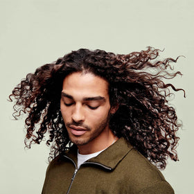DevaCurl jar on shower shelf showing everyday use and frizz-reducing benefit