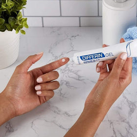 Applying Differin with fingertip to cheek for targeted acne prevention