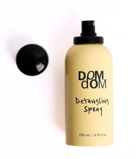 Dom Dom spray on styled hair in bathroom setting, eases brushing and preps for heat