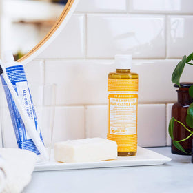 Dr. Bronner's citrus bottle pouring into water demonstrating dilution for cleaning