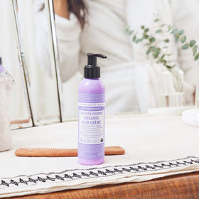 Dr. Bronner's hand applying creme to hair demonstrating easy distribution and light hold benefit