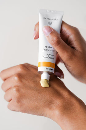 Dr. Hauschka jar in hand for scale showing compact travel-friendly benefit