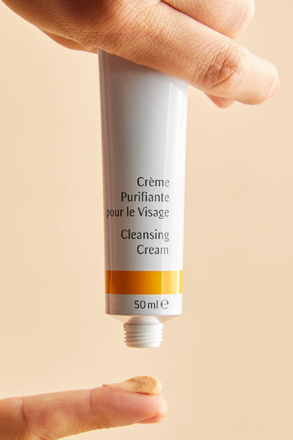 Dr. Hauschka tube held in hand illustrating 1.7 fl oz pocket-friendly size and travel convenience