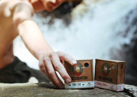 Dr. Squatch bar beside coconut and pine visuals displaying natural-ingredient benefit
