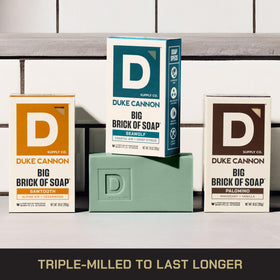 Duke Cannon bars next to a hand showing scale and benefit of oversized 10 oz bricks
