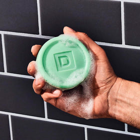 Duke Cannon puck on shower ledge demonstrating durable soap staying solid between uses
