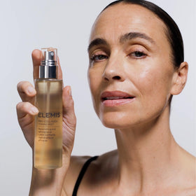 ELEMIS bottle next to hand showing 150ml scale and travel-friendly size