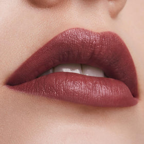 Estée Lauder lipstick next to coin to show compact size and portability benefit