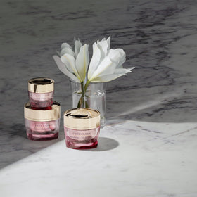 Estée Lauder 1.7 ounce jar next to common items for size reference