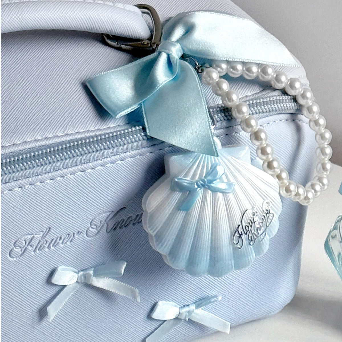 Flower Knows pearl keychain detail clipped to shell offering portable, decorative carry