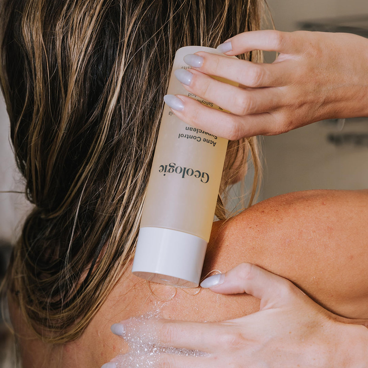 Geologie body wash being applied to skin showing targeted treatment of back breakouts