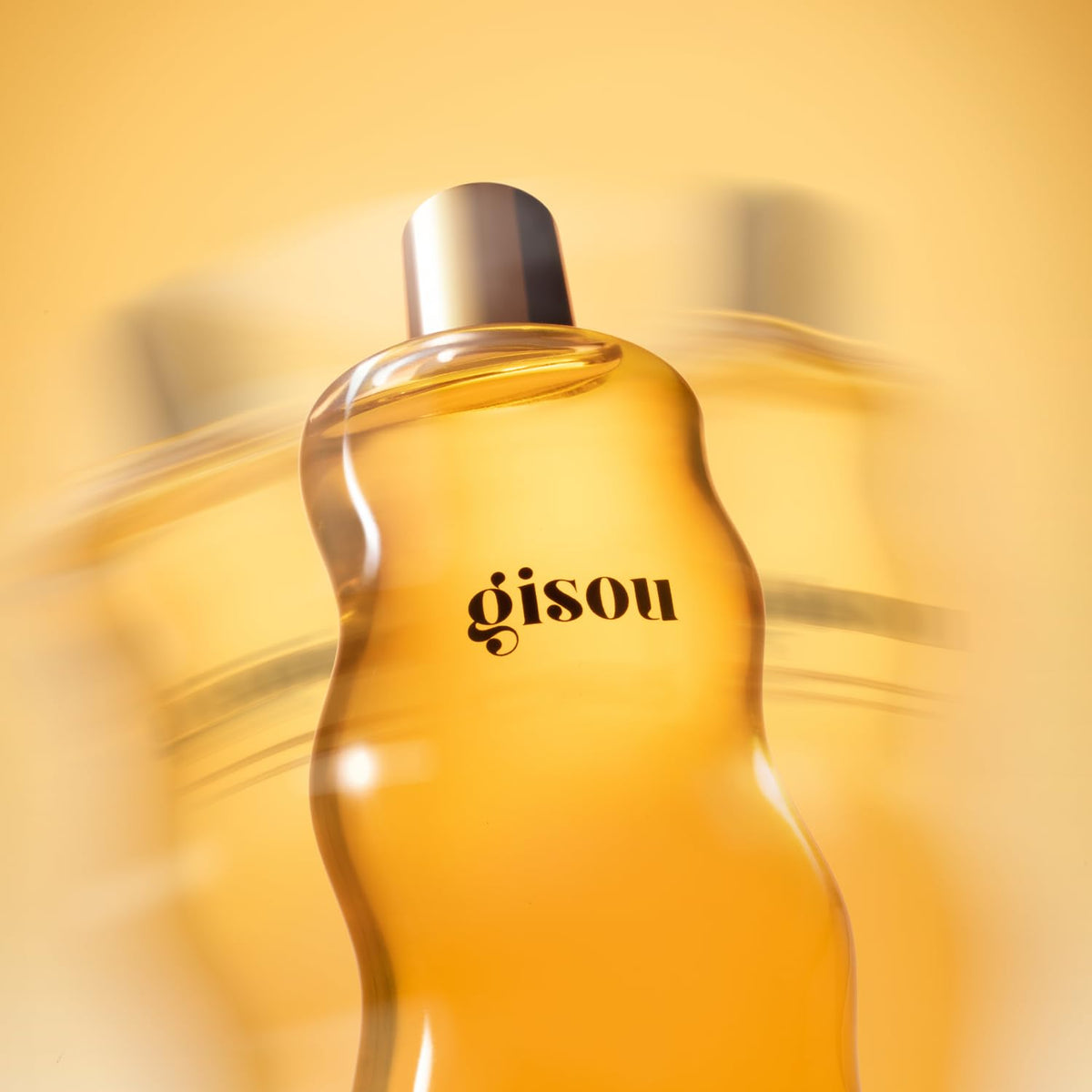 Gisou bottle beside hand for scale highlighting travel-friendly 1.5 fl oz