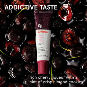 Glossier Balm Dotcom swatch on skin showing sheer burgundy color and moisturization