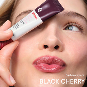 Glossier Balm Dotcom tube in hand showing travel size convenience and easy application