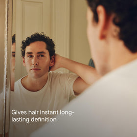 Hands applying Harry's putty into hair for controlled, touchable styling