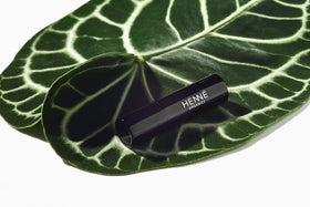 Henné Organics lip balm held in hand showing compact travel size benefit