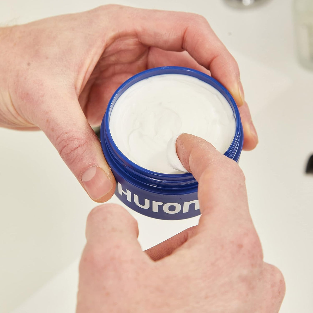 Huron jar in hand for scale showing compact travel-friendly size