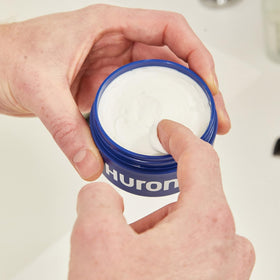 Huron jar in hand for scale showing compact travel-friendly size