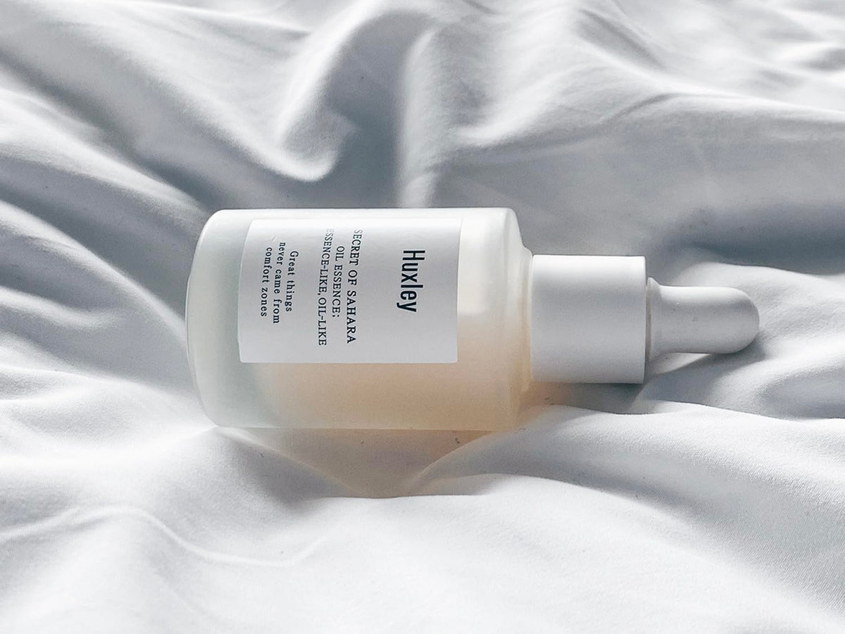 Huxley bottle on vanity with skincare items, suggests daily routine integration