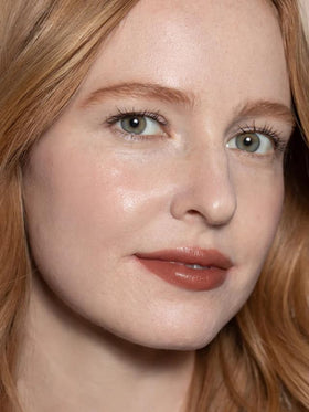 ILIA application step rubbing balm on lips demonstrating moisturized finish