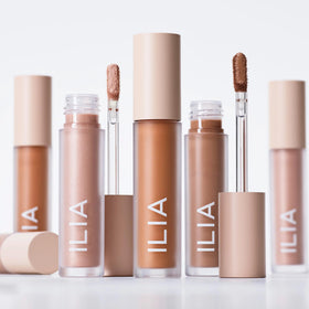 ILIA product next to fingers for scale to show compact travel-friendly size