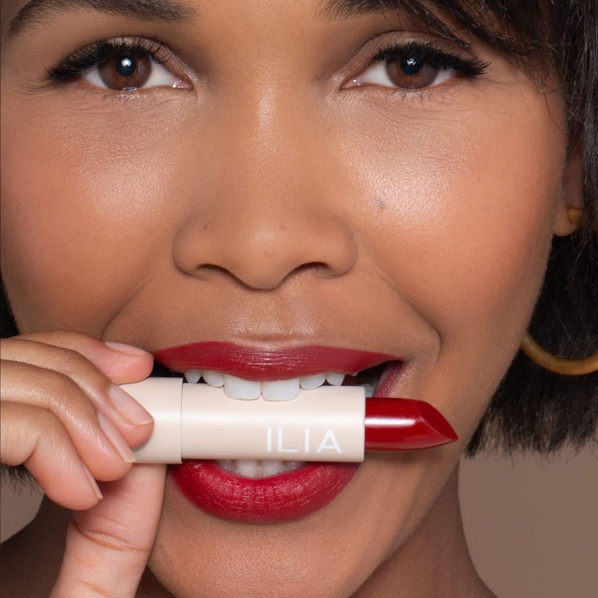 ILIA swatch of Tango lipstick texture on skin demonstrating even, high-impact color
