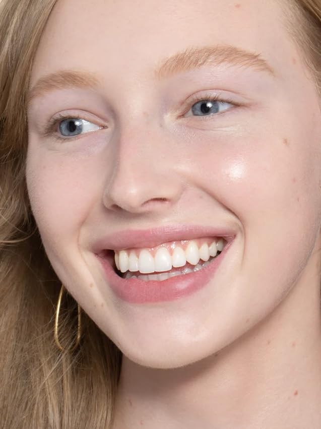ILIA model applying skin tint in natural light demonstrating breathable coverage and fresh finish