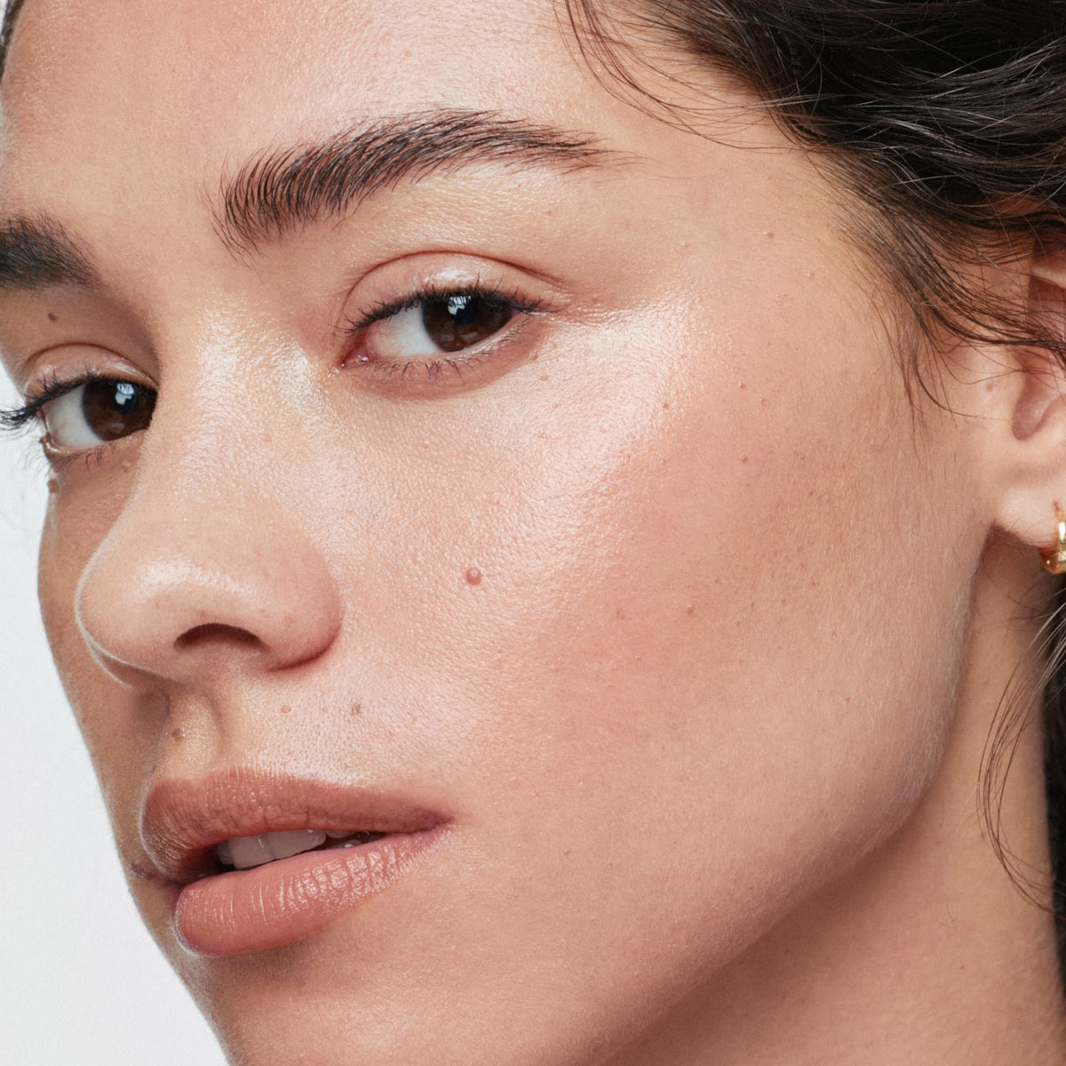 ILIA swiped on skin close-up showing champagne-pearl glow and natural radiance