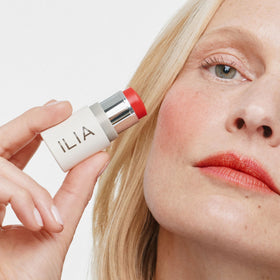 ILIA multi‑stick on lips closeup showing rich poppy red tint and conditioning feel