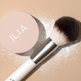 ILIA powder being picked up on a brush for smooth, even application