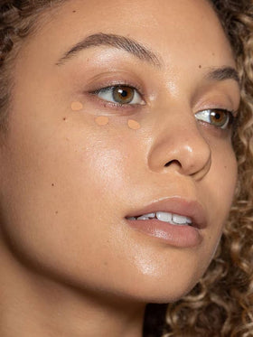 ILIA concealer held in hand demonstrating compact travel size