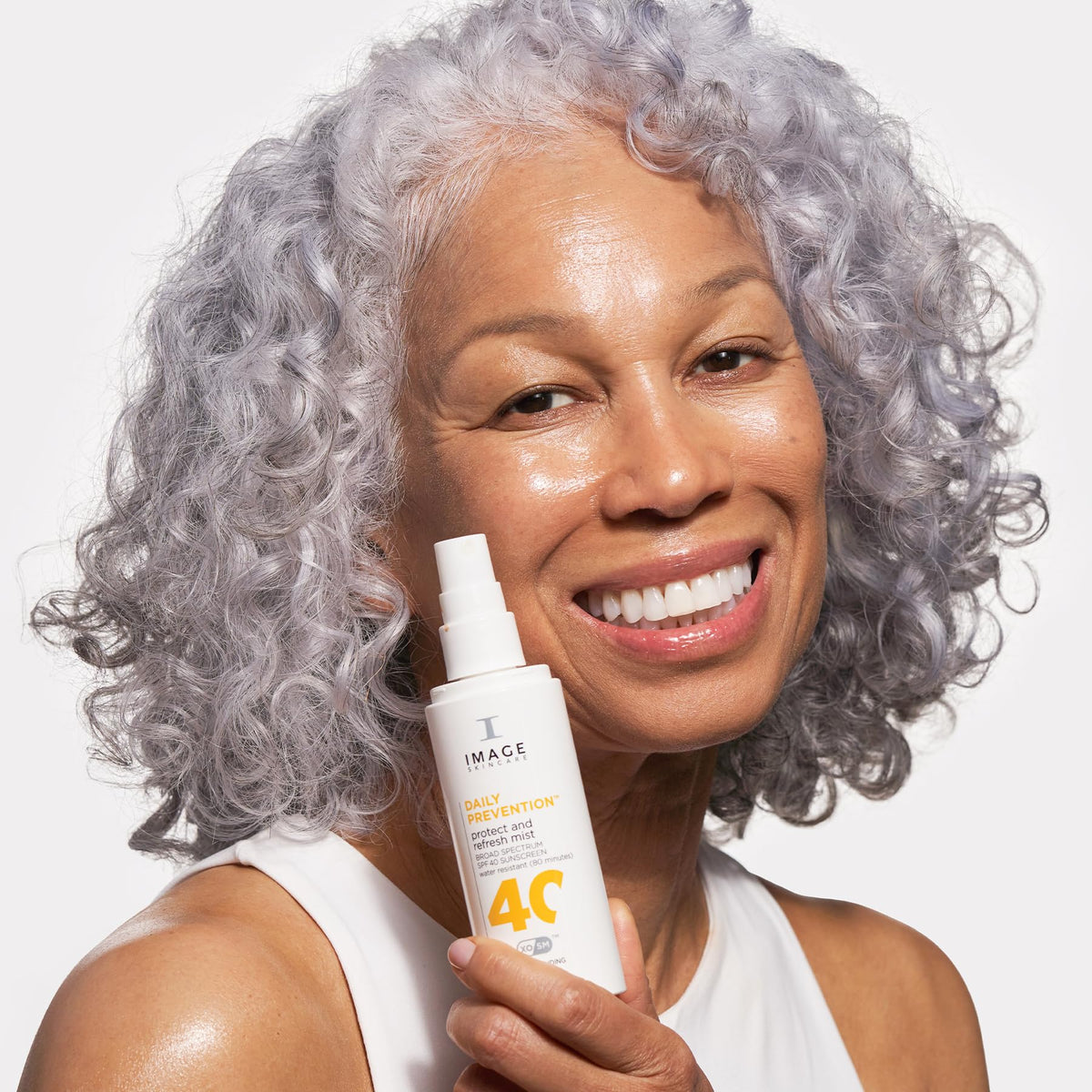 IMAGE Skincare mist sprayed over makeup showing clear application that preserves makeup