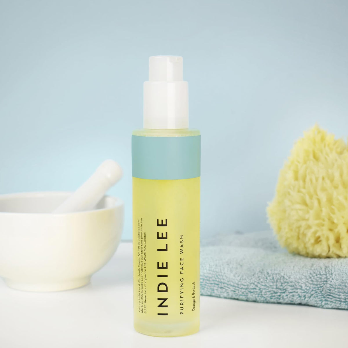 Indie Lee bottle held in hand to show 4oz scale and travel-friendly size