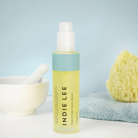 Indie Lee bottle held in hand to show 4oz scale and travel-friendly size