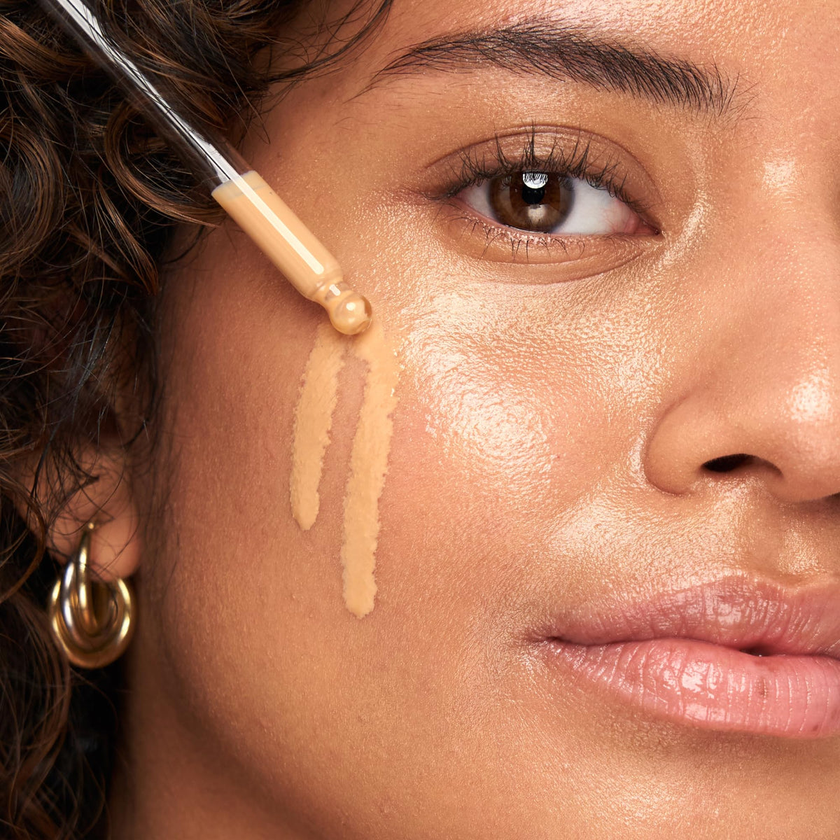 Model applying Indie Lee primer to face, creates even base for makeup