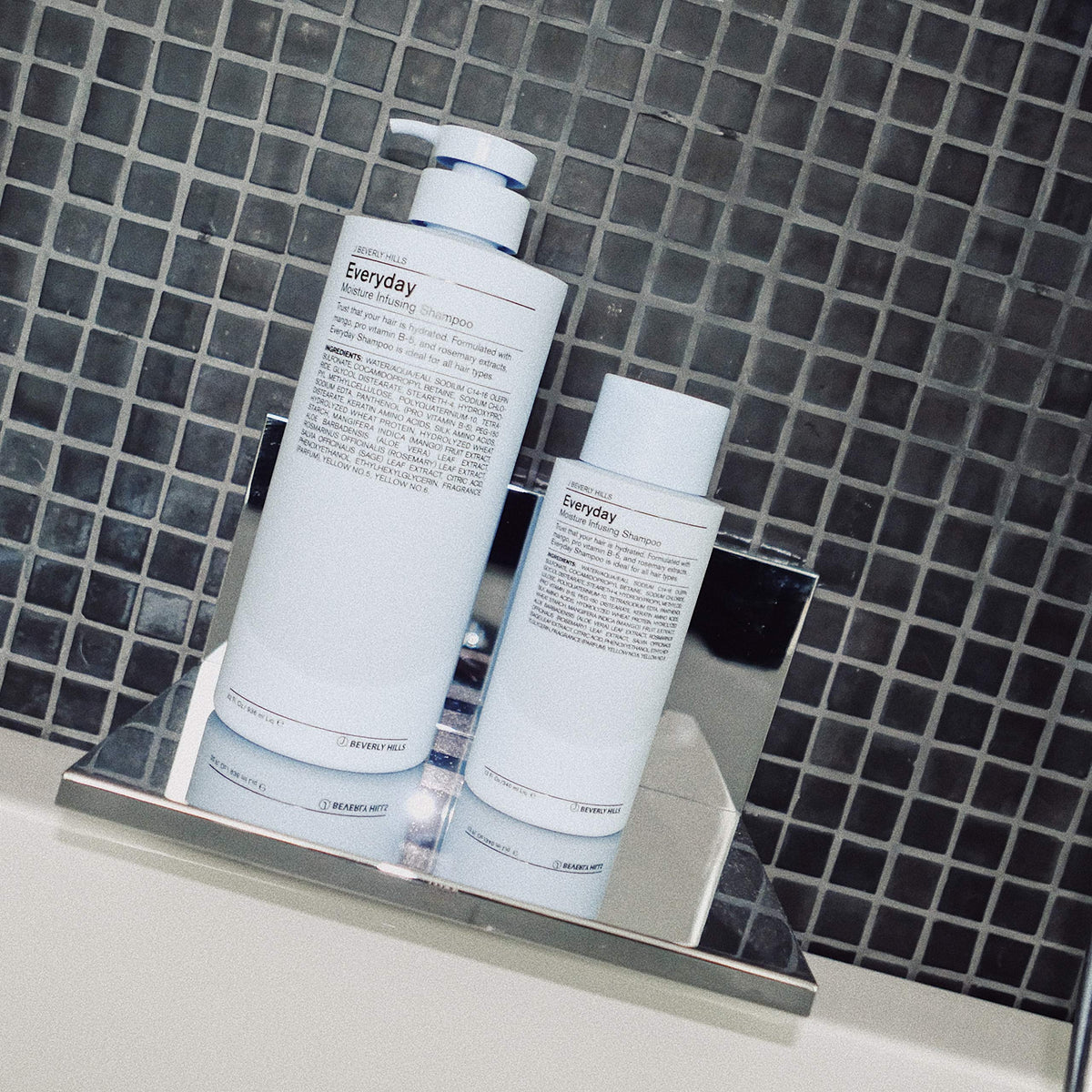 Hand holding J Beverly Hills 12 oz bottle to show scale and travel-friendly size benefit