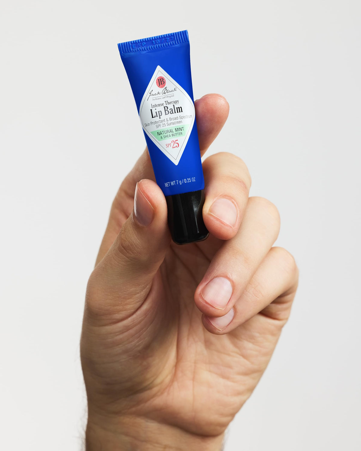 Person applying Jack Black lip balm outdoors demonstrating SPF protection during activity